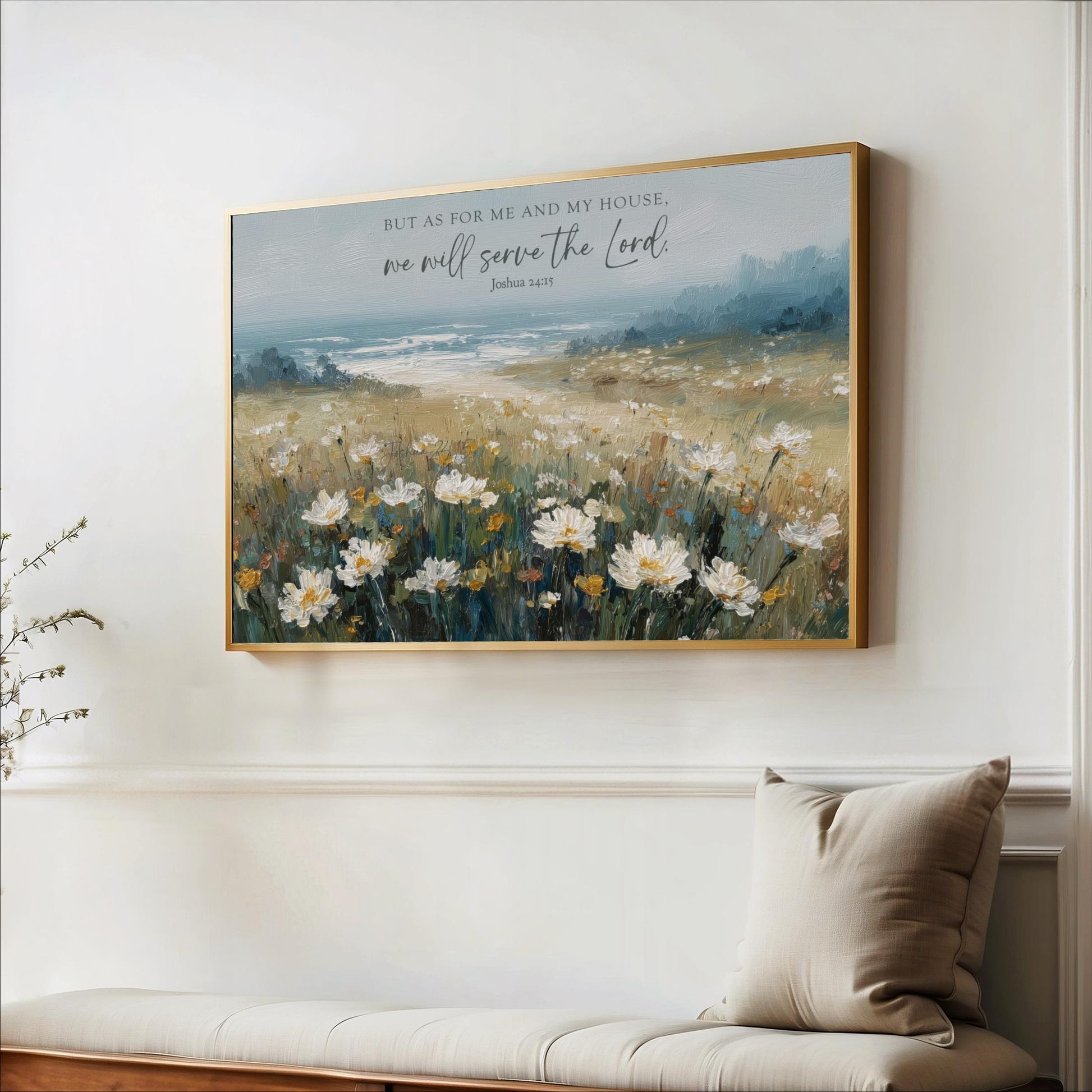 A framed painting of a field of white flowers hangs on a white wall, with a quote from the Bible above it.