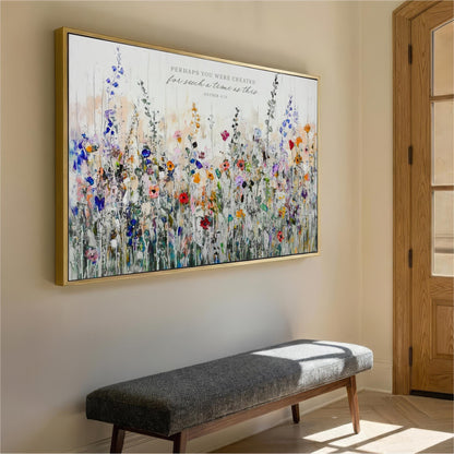 a large, colorful painting of a field of flowers hanging on a wall. The painting is framed in gold and is the main focus of the room. In front of the painting, there is a gray bench, and a wooden door can be seen on the right side of the image.