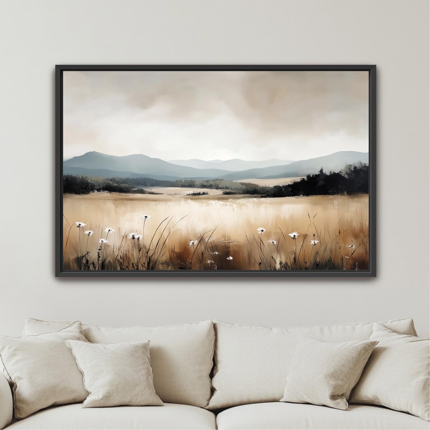 a framed landscape painting hanging on a wall above a beige couch.