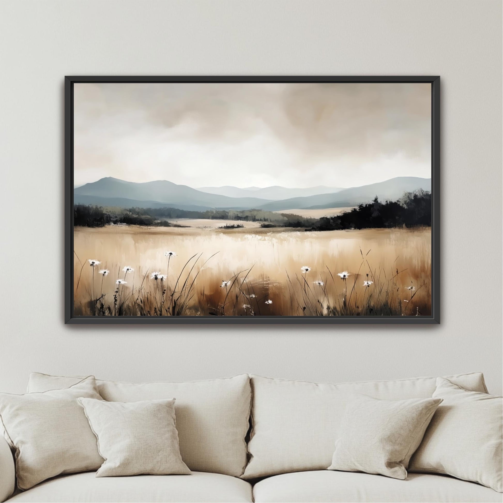 a framed landscape painting hanging on a wall above a beige couch.