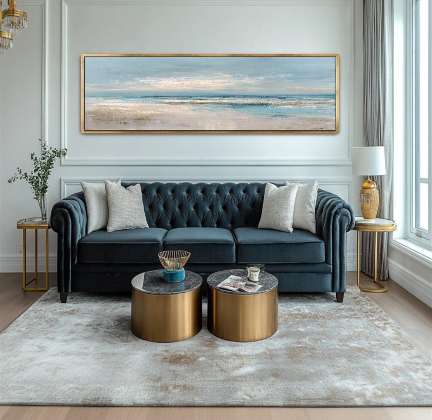 A modern living room with a blue tufted sofa, two round coffee tables, and a large painting of a beach scene on the wall.