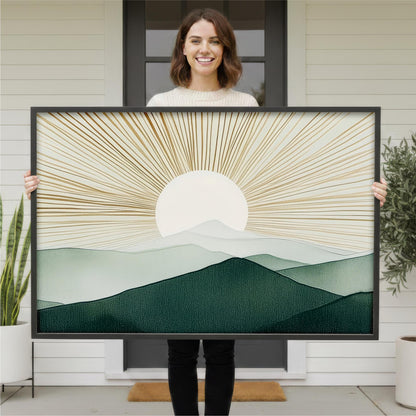 A woman is holding a large framed print of a landscape with mountains and a sun in the background.