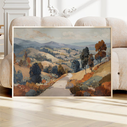a large landscape painting displayed on a wooden floor, with a sofa in the background.
