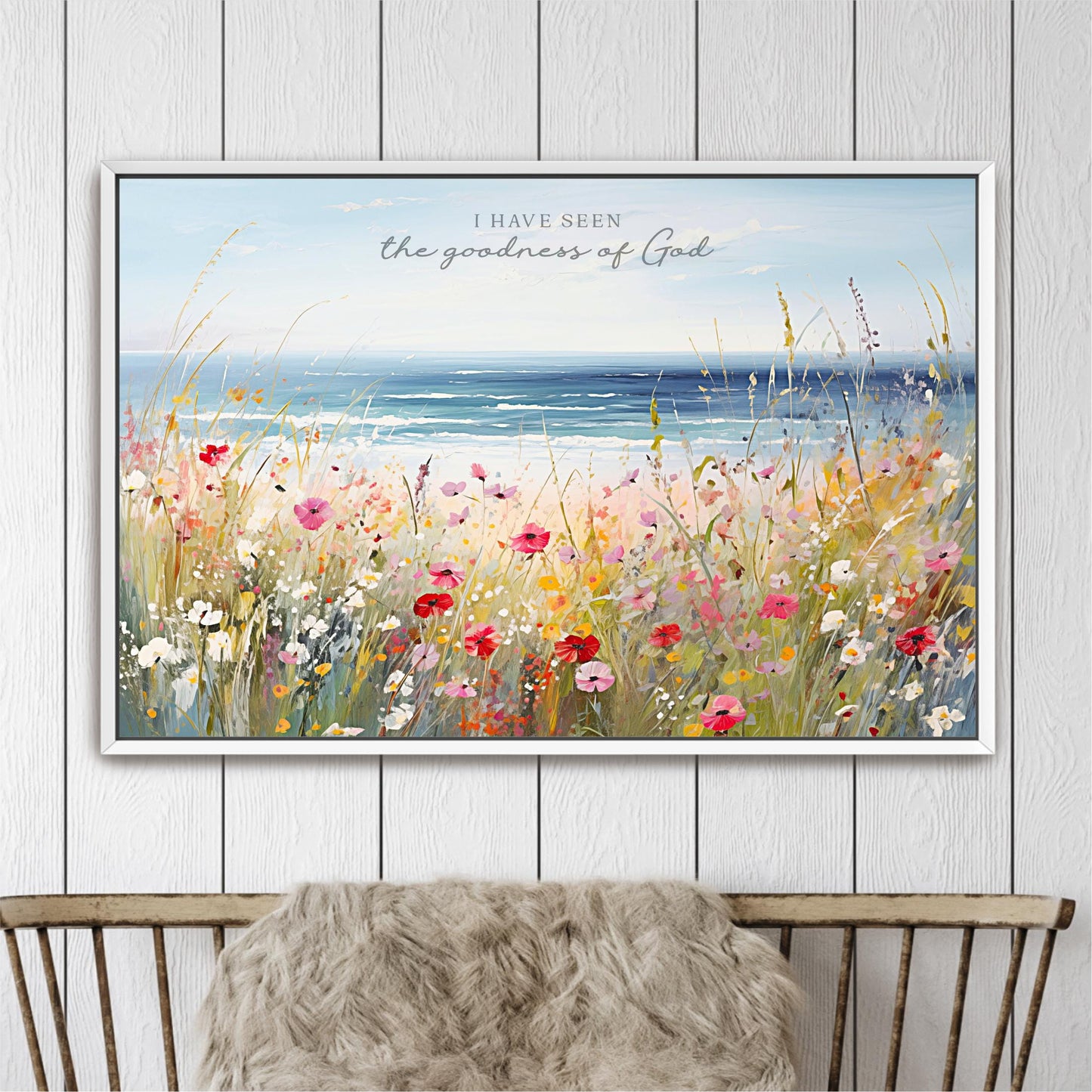 The image is a framed painting depicting a vibrant field of flowers with a serene body of water in the background.