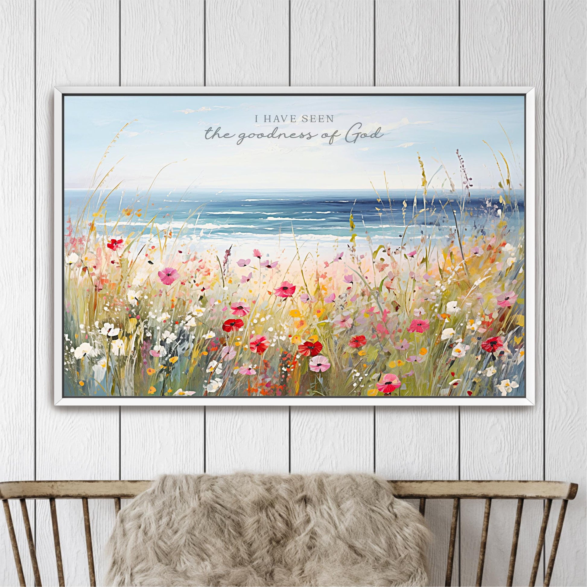 The image is a framed painting depicting a vibrant field of flowers with a serene body of water in the background.