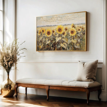 a large painting of a field of sunflowers hanging on a white wall, with a wooden bench and a vase of flowers placed next to it.