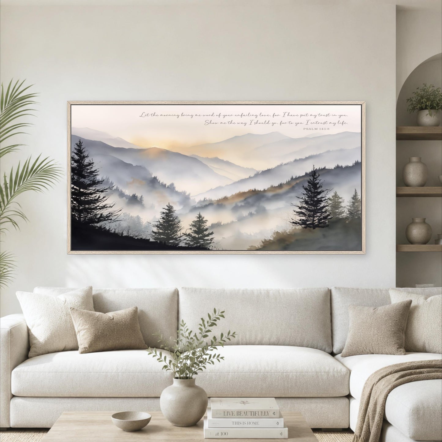 a large framed landscape painting hanging on a wall above a white sofa in a living room.