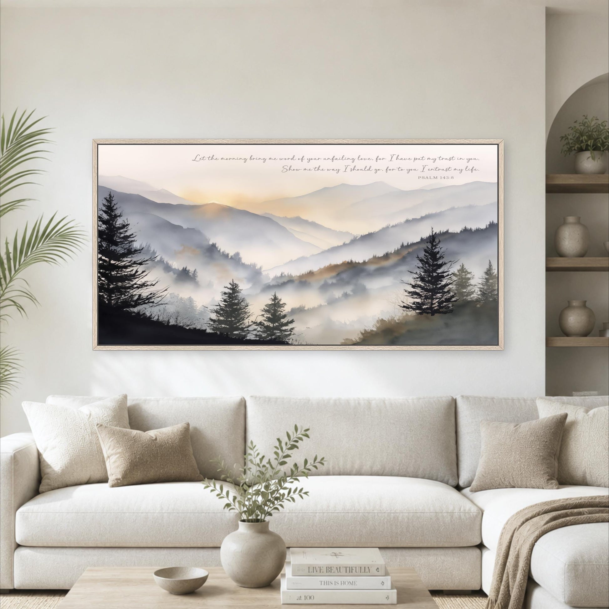 a large framed landscape painting hanging on a wall above a white sofa in a living room.