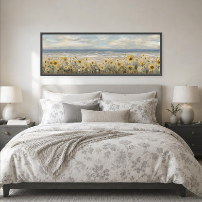 a large bed with a floral comforter and pillows, and a framed painting of a field of flowers above it. The painting is hanging on the wall above the bed.