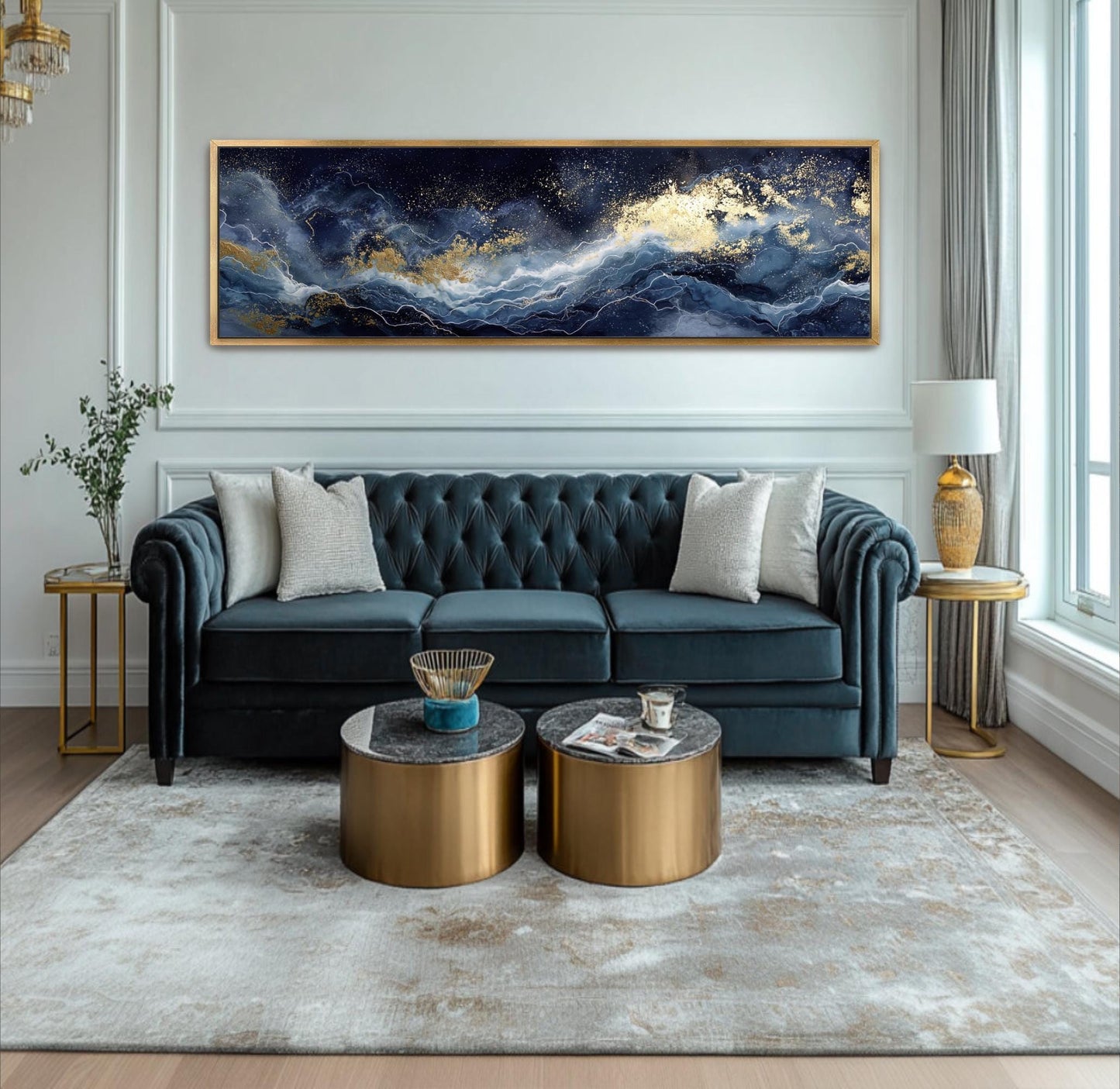 A luxurious living room with a large blue velvet sofa, two round coffee tables, and a large gold-framed painting depicting a seascape with a blue sky and white clouds.