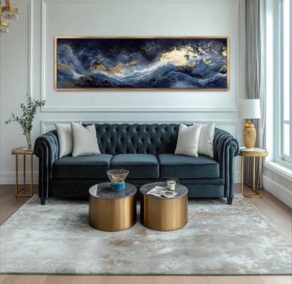 A luxurious living room with a large blue velvet sofa, two round coffee tables, and a large gold-framed painting depicting a seascape with a blue sky and white clouds.