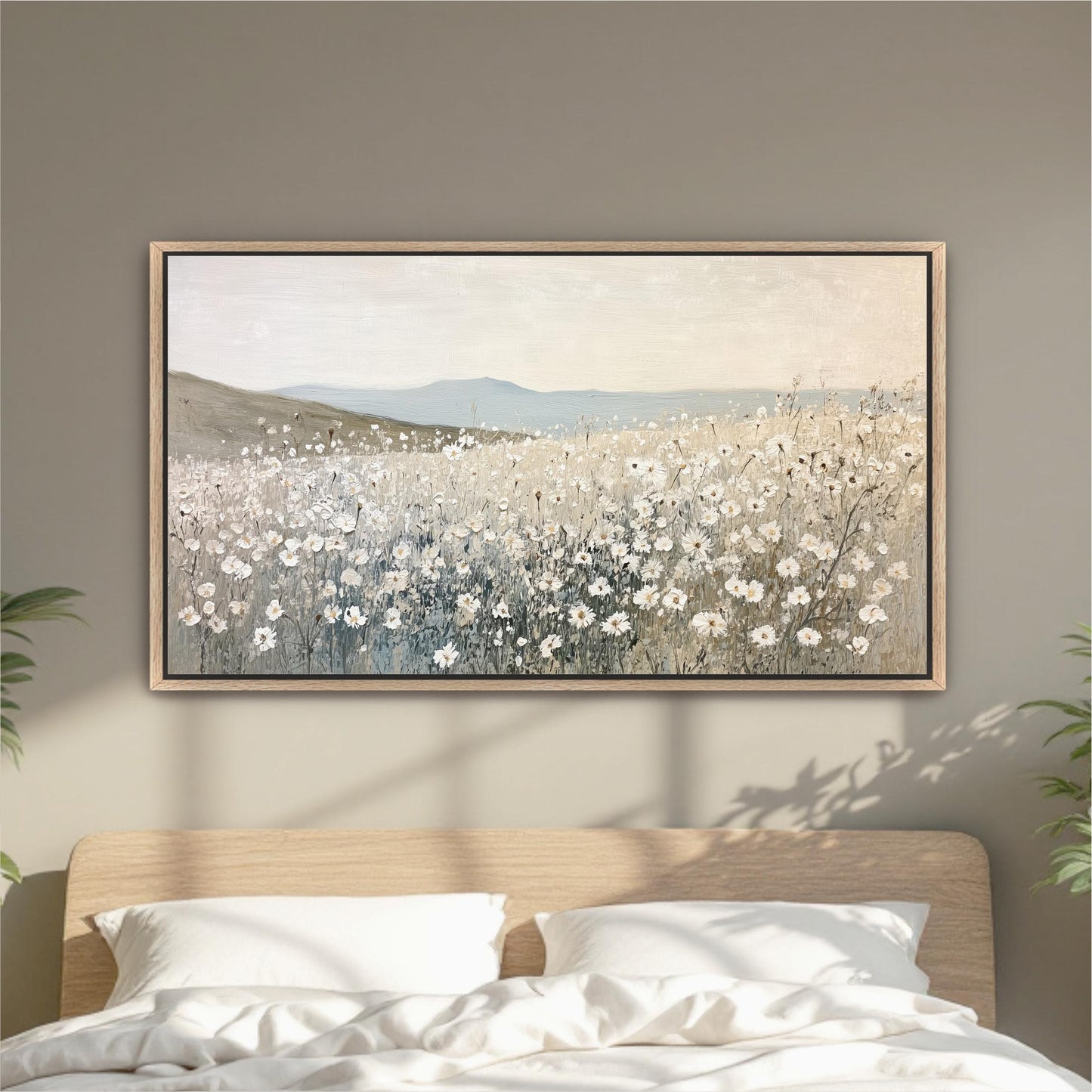 a large painting of a field of white flowers hanging on a wall above a bed with white pillows.