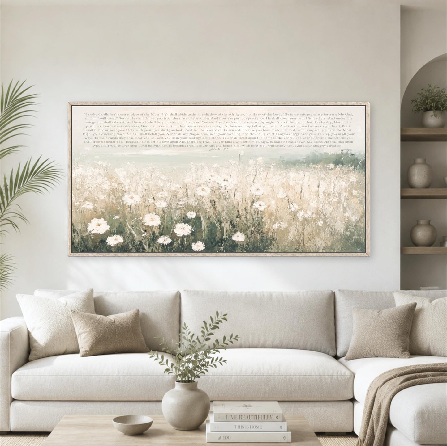 a large framed painting of a field of flowers hanging on a wall above a white sofa in a living room.