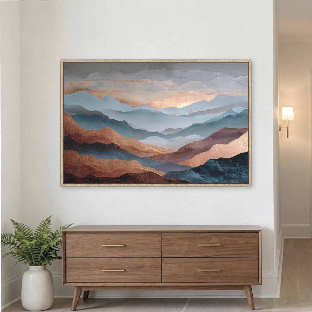a large painting of mountains hanging on a white wall above a wooden dresser with four drawers.