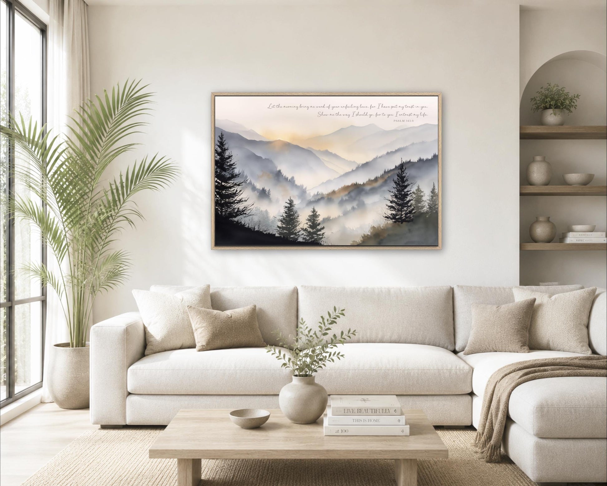 a serene living room with a large framed landscape painting hanging on the wall, featuring a mountain range with trees and a hazy, golden sky. The room is decorated with a white sofa, a coffee table, and a potted plant, creating a cozy and inviting atmosphere.
