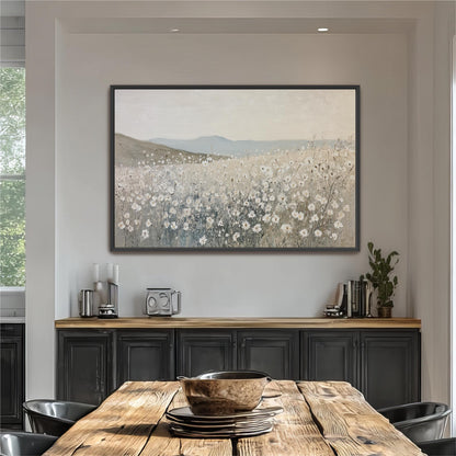 a large painting of a field with flowers hanging on the wall above a wooden dining table with chairs.