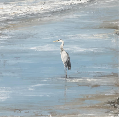 A white heron stands in the water, its long neck and legs visible as it appears to be gazing out at the ocean.