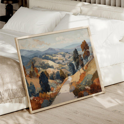 a large landscape painting with a winding road and trees in the foreground, displayed on a wooden floor next to a white bed.