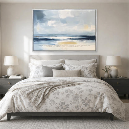 a large bedroom with a bed, nightstands, and a painting hanging above the bed. The painting depicts a serene landscape with a blue sky, white clouds, and a sandy beach. The room has a neutral color scheme with gray and white tones, creating a calm and peaceful atmosphere.