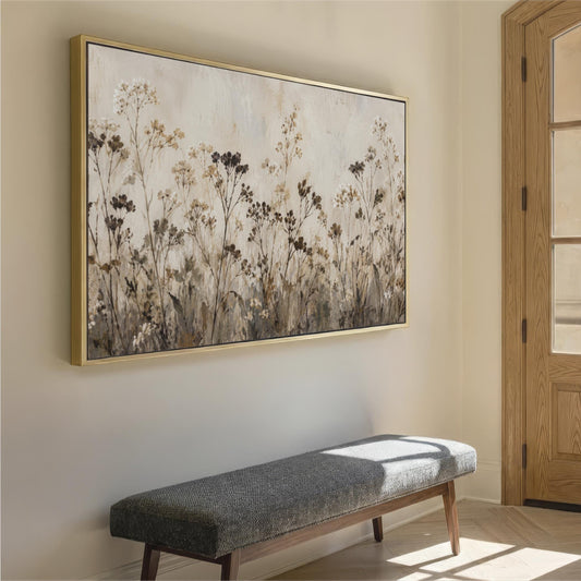 a large, framed painting of a field of flowers hanging on a wall, with a gray bench placed in front of it.