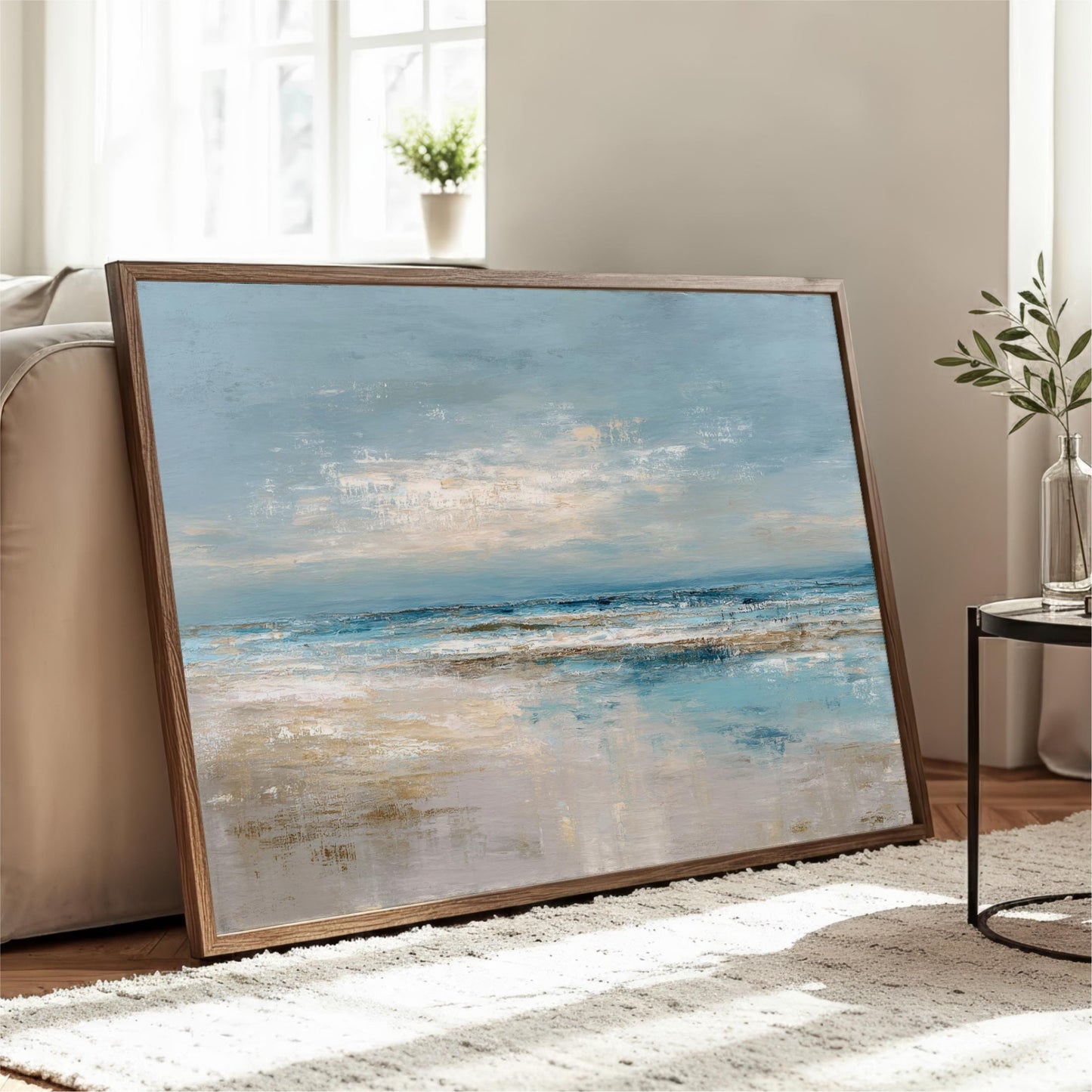 a large framed painting of a serene landscape depicting a beach scene with a blue sky and ocean.