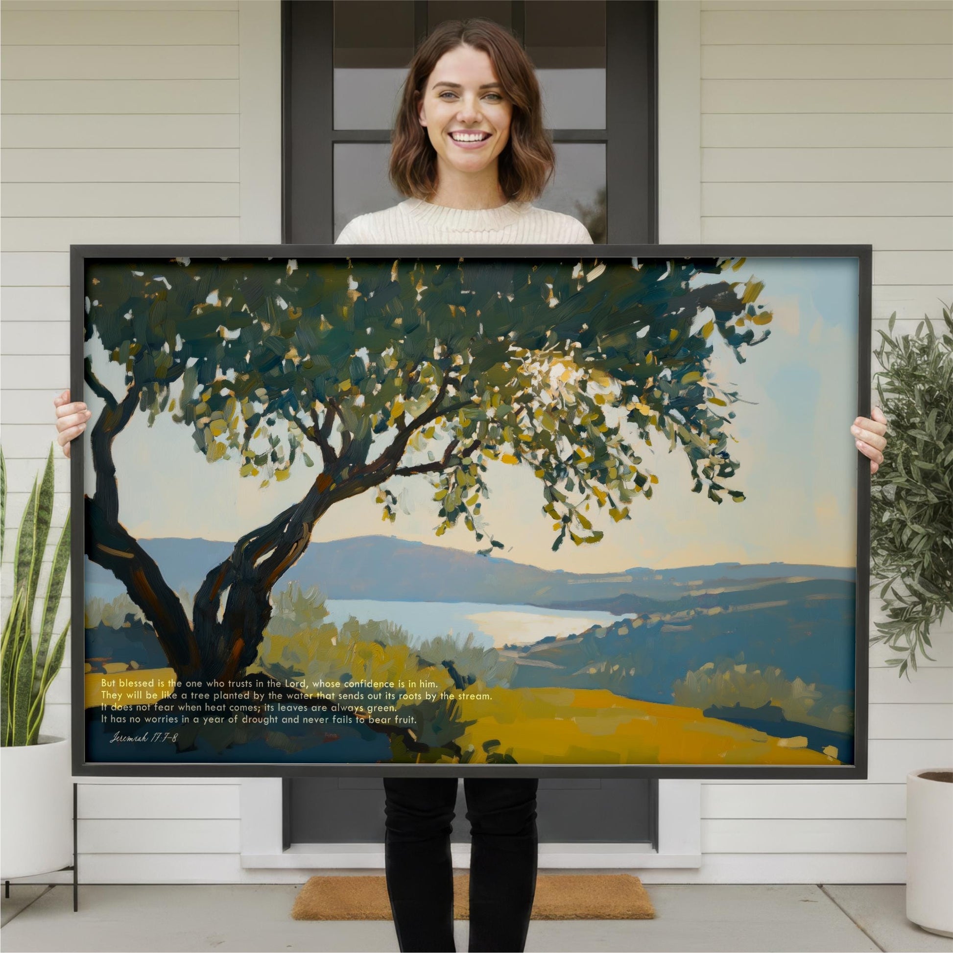 A woman stands in front of a large painting, holding it up to display the artwork.