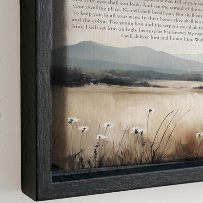 The image is a framed painting depicting a serene landscape with a field of tall grass and white flowers. The painting is framed in a black wooden frame and is hung on a wall.