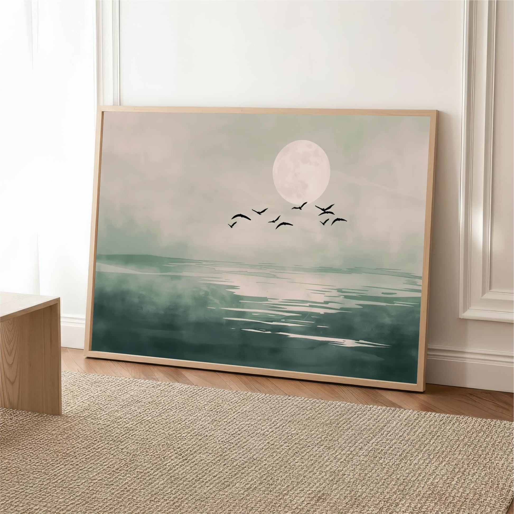 A framed painting depicting a serene landscape with a large moon, birds flying over a body of water.