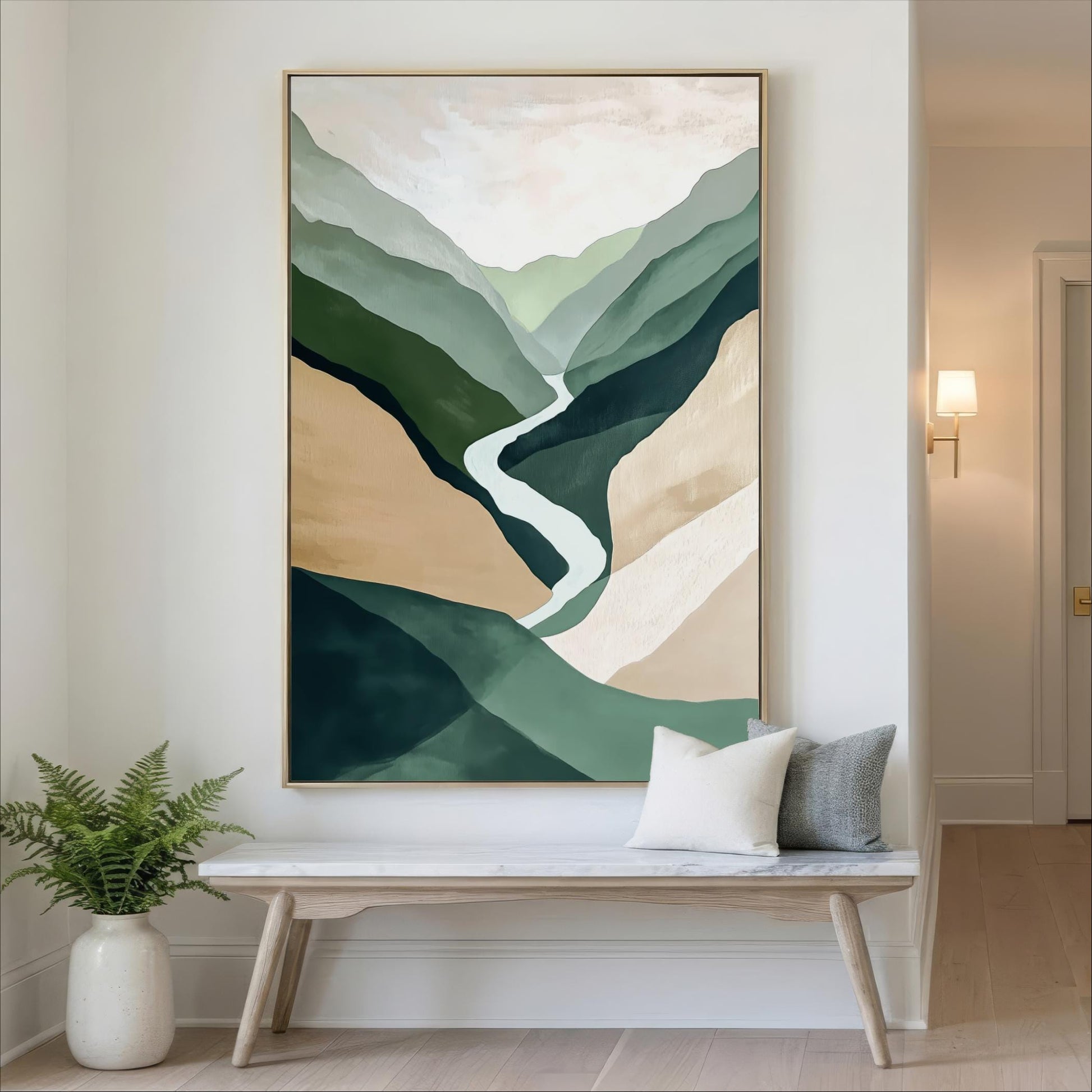 a large abstract painting hanging on a wall, depicting a winding path through a mountainous landscape. The painting is framed in gold and is placed above a wooden bench with two pillows. The room has a minimalist and modern design, with a white wall and a vase of greenery on the floor.