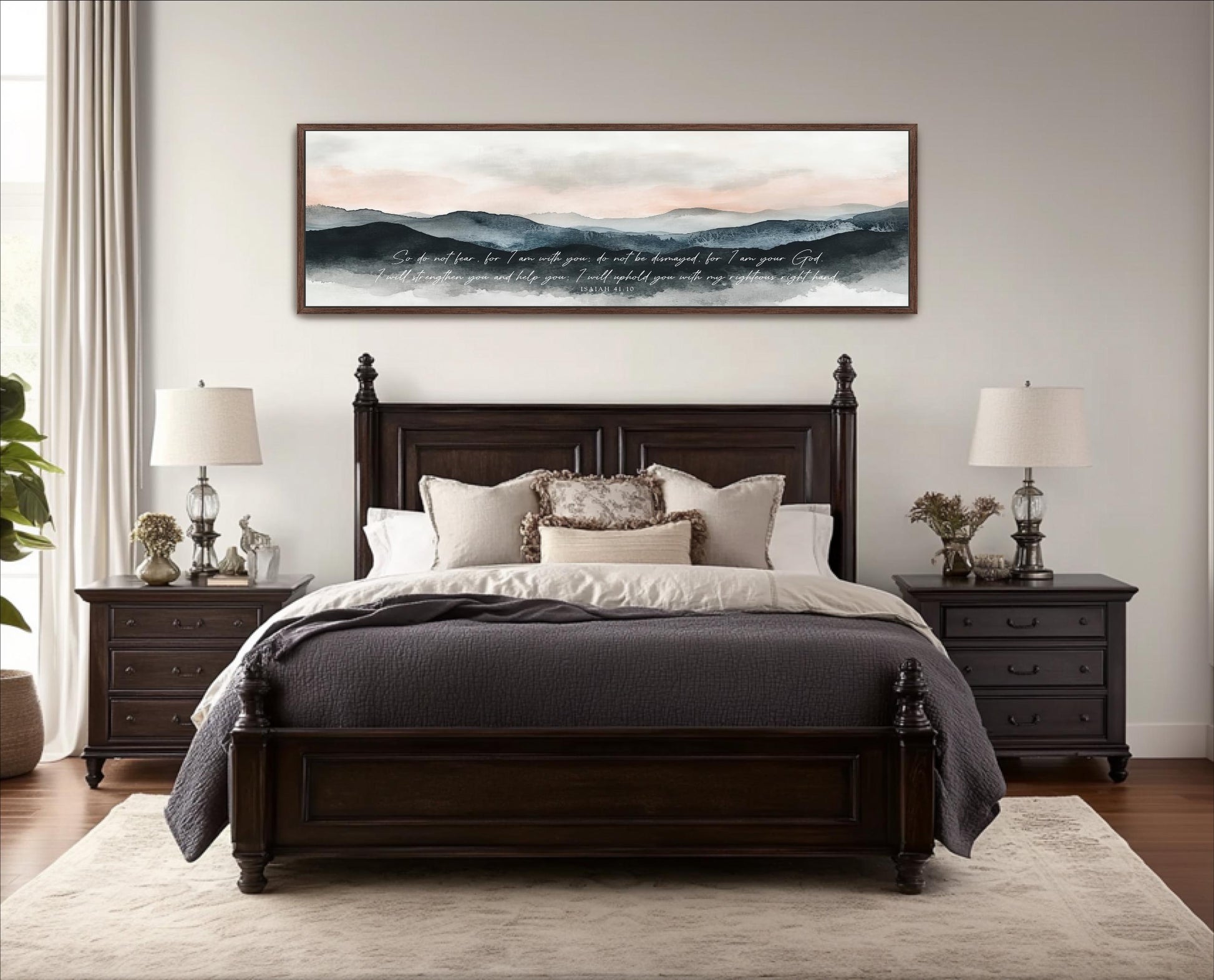 a large, dark wooden bed with a gray comforter and pillows, flanked by two nightstands with lamps. Above the bed is a large, framed landscape painting depicting a mountain range with a cloudy sky.