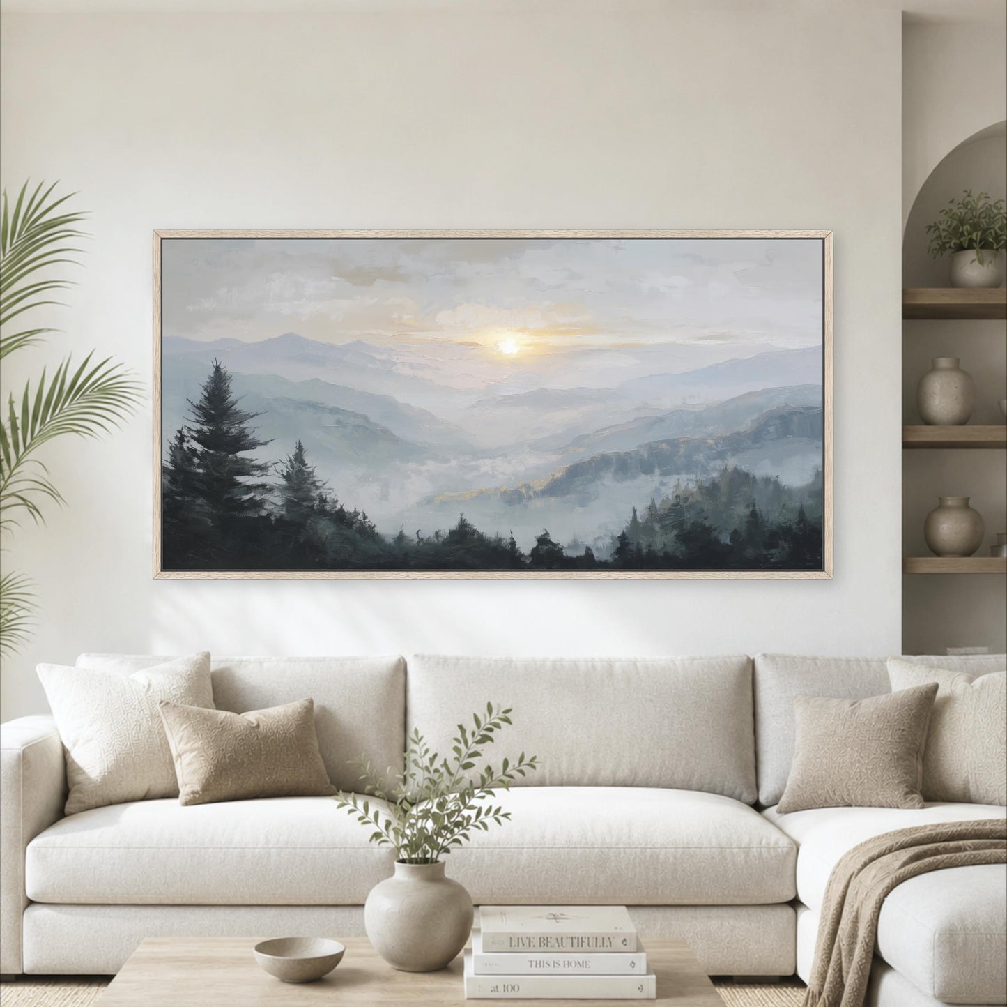 a large landscape painting hanging on a wall above a white sofa in a living room.