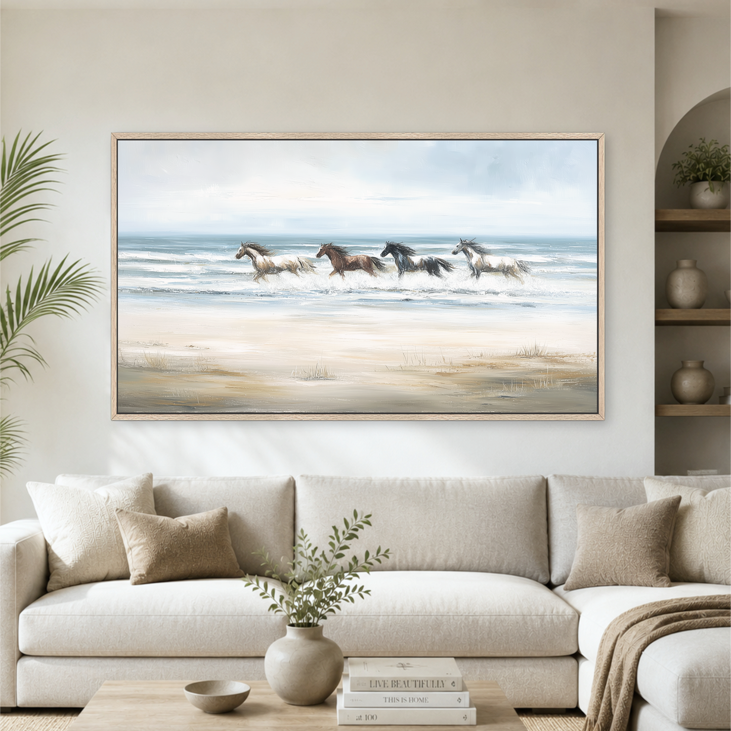 a large painting of horses running on a beach, hanging on a wall above a white sofa in a living room setting.