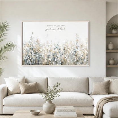 a large framed print of a field of flowers hanging on a wall above a white sofa in a living room.