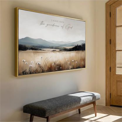 a large framed painting of a serene landscape with mountains, grass, and wildflowers hanging on a wall.