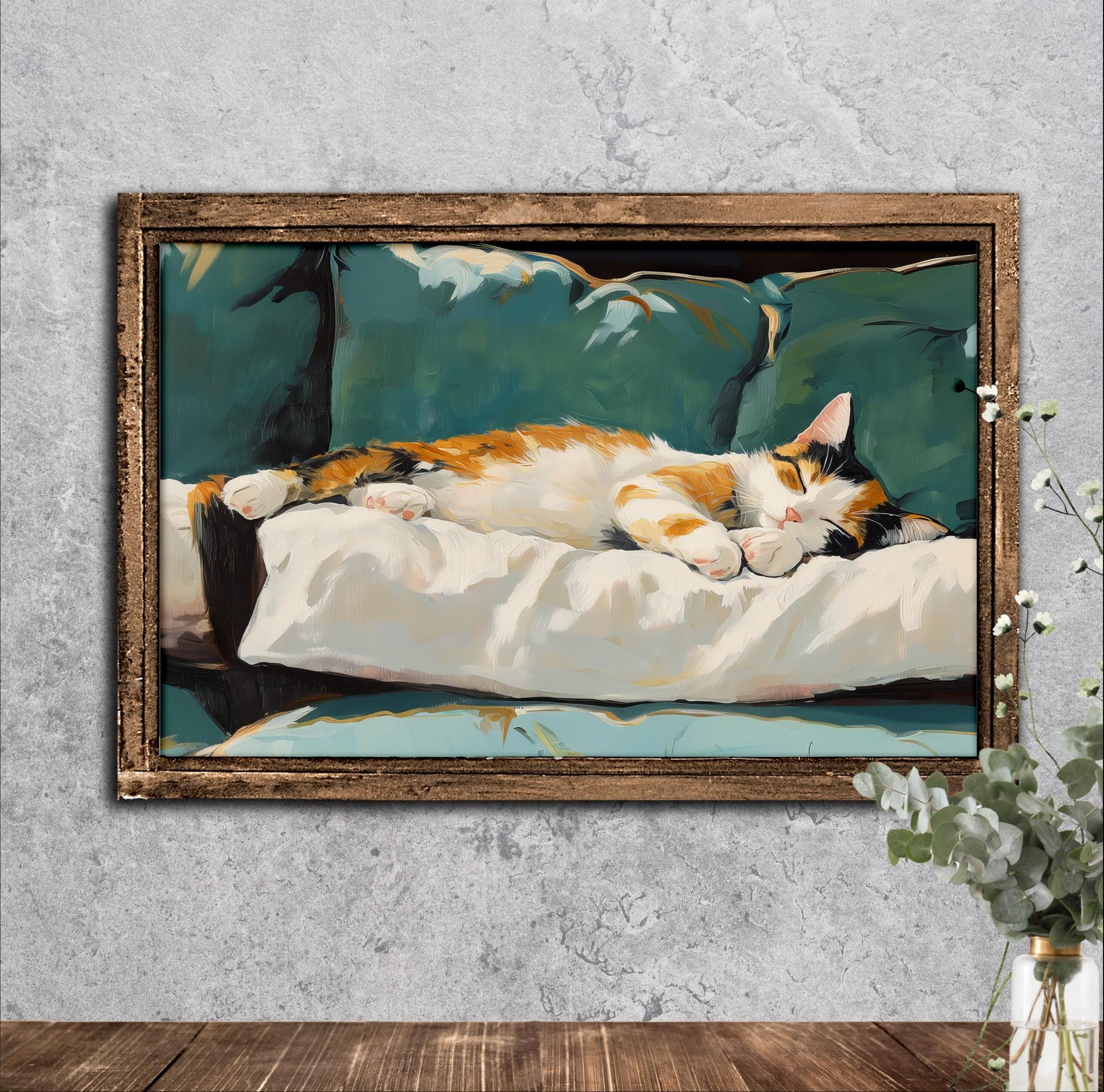 A framed painting of a cat sleeping on a white pillow, set against a green background.