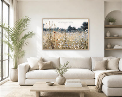 a serene living room with a large white sofa, a wooden coffee table, and a framed painting of a field of flowers hanging on the wall.