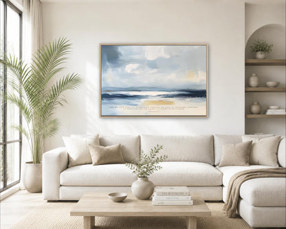 a serene living room with a large painting of a beach scene hanging on the wall above a white sofa. The room is decorated with a potted plant, a vase with greenery, and a stack of books on a coffee table.