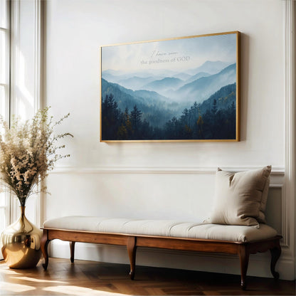 a serene indoor setting with a large framed landscape painting hanging on the wall above a wooden bench. The painting depicts a mountainous, forested scene with a misty, hazy atmosphere. The bench is positioned in front of the painting, creating a cozy and inviting space. A vase of flowers is also present in the room, adding a touch of natural beauty to the scene.