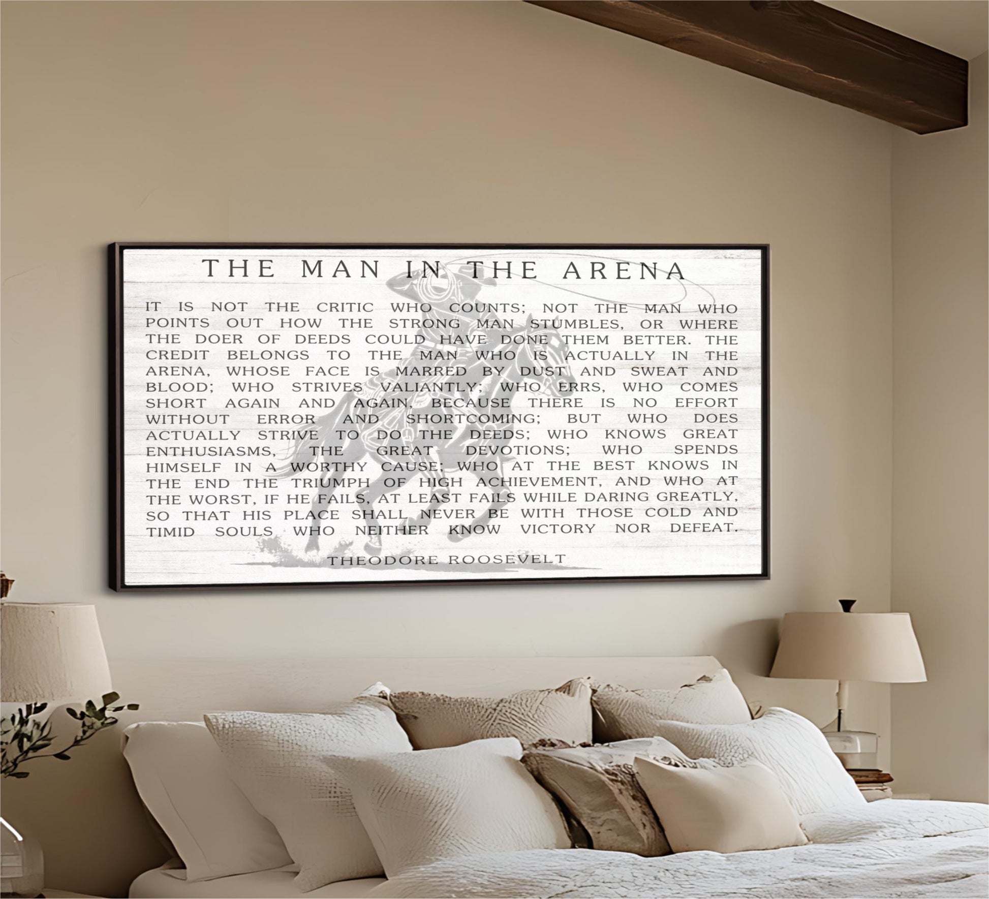 The image is a framed quote by Theodore Roosevelt, which is displayed on a wall above a bed with pillows.