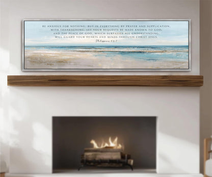 The image is a framed artwork hanging on a wall above a fireplace. The artwork depicts a serene landscape with a calm body of water and a peaceful atmosphere. The text above the artwork reads "Be anxious for nothing, but in everything by praise and supplication, with Thanksgiving, let your requests be made known to God, and the peace be given, which represses all understanding, and will guard your hearts and minds through Christ Jesus."