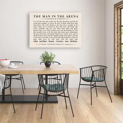 a framed quote by Theodore Roosevelt, "The Man in the Arena", displayed on a wall above a wooden dining table with black chairs.