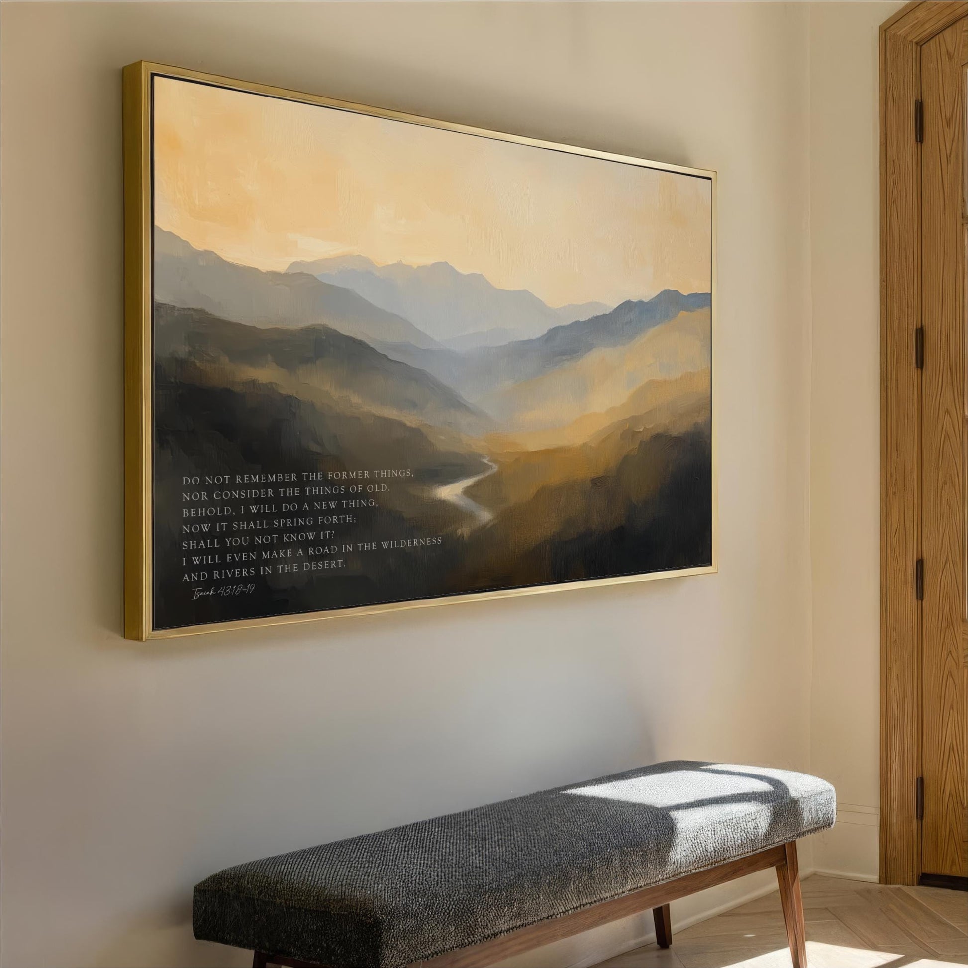 a large landscape painting hanging on a wall, depicting a mountainous scene with a winding river. The painting is framed in gold and is the main focus of the room. In front of the painting, there is a gray bench, and a wooden door can be seen on the right side of the image.