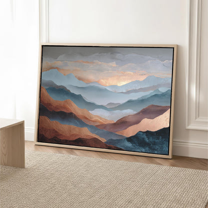 a large framed painting of mountains with a warm, golden-toned sky in the background.