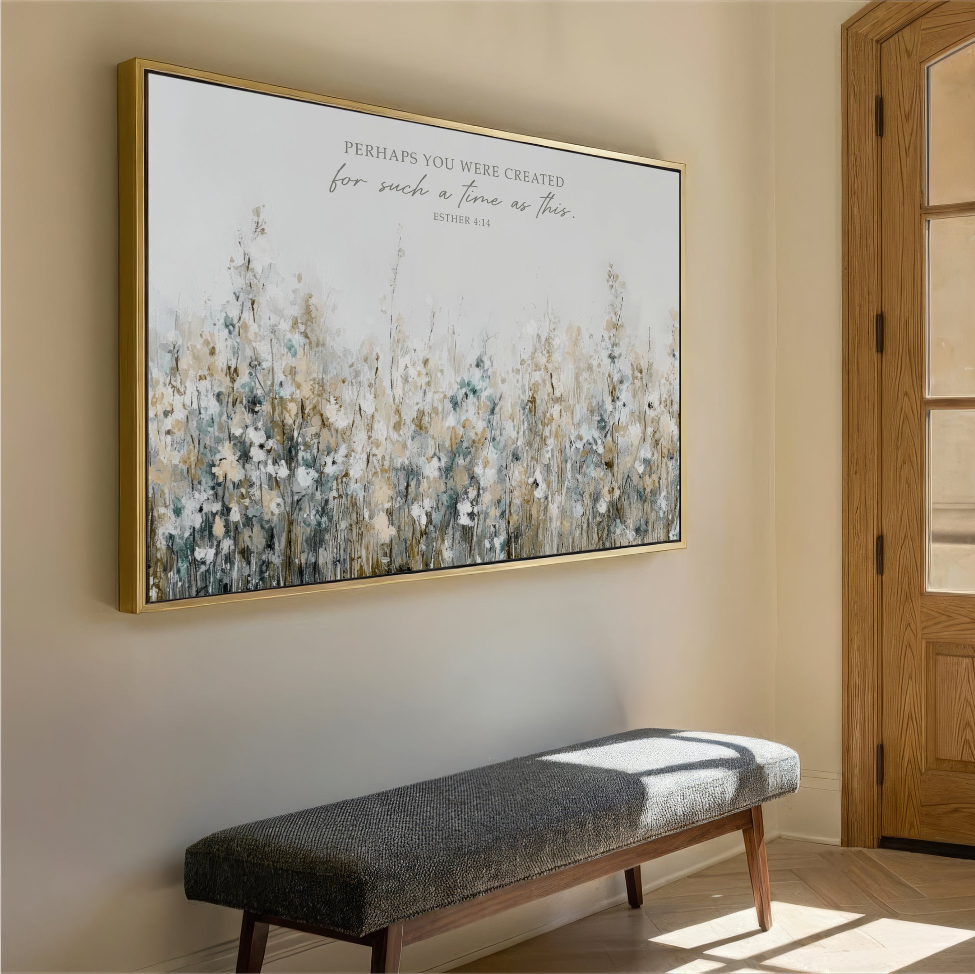 a large framed painting of a field of flowers hanging on a wall, with a gray bench placed in front of it.