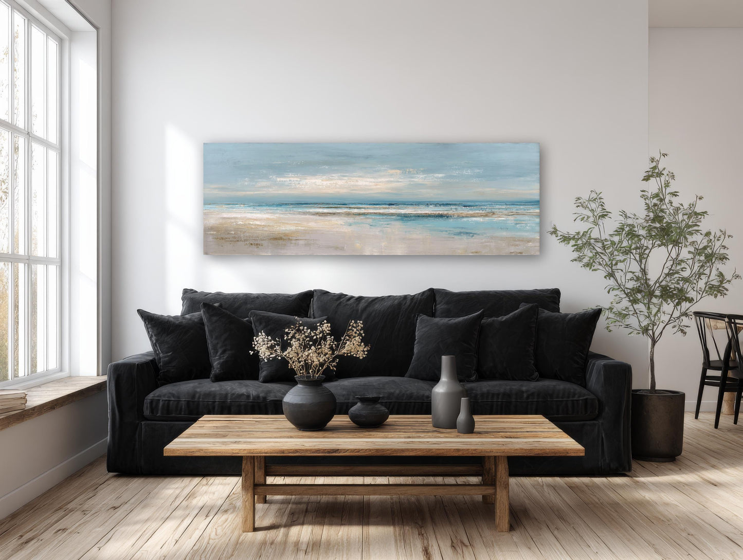 a modern living room with a large window, a black sofa, a wooden coffee table, and a painting of a beach scene hanging on the wall above the sofa.
