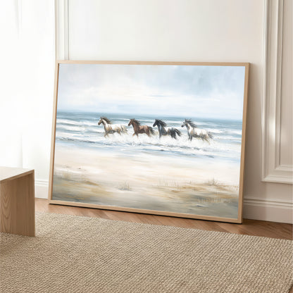 A framed painting depicting a group of horses running across a sandy beach with the ocean in the background.