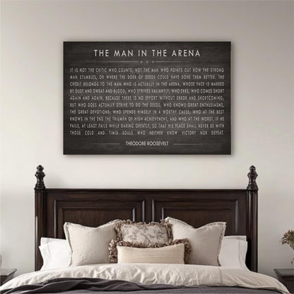 a large black framed quote by Theodore Roosevelt hanging on a white wall above a bed with a dark wooden headboard.