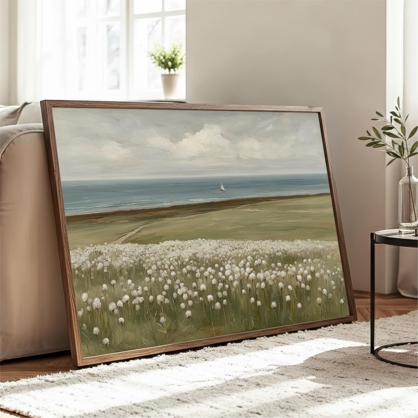 A large framed painting depicting a serene landscape with a field of white flowers, a sailboat on the water, and a cloudy sky.