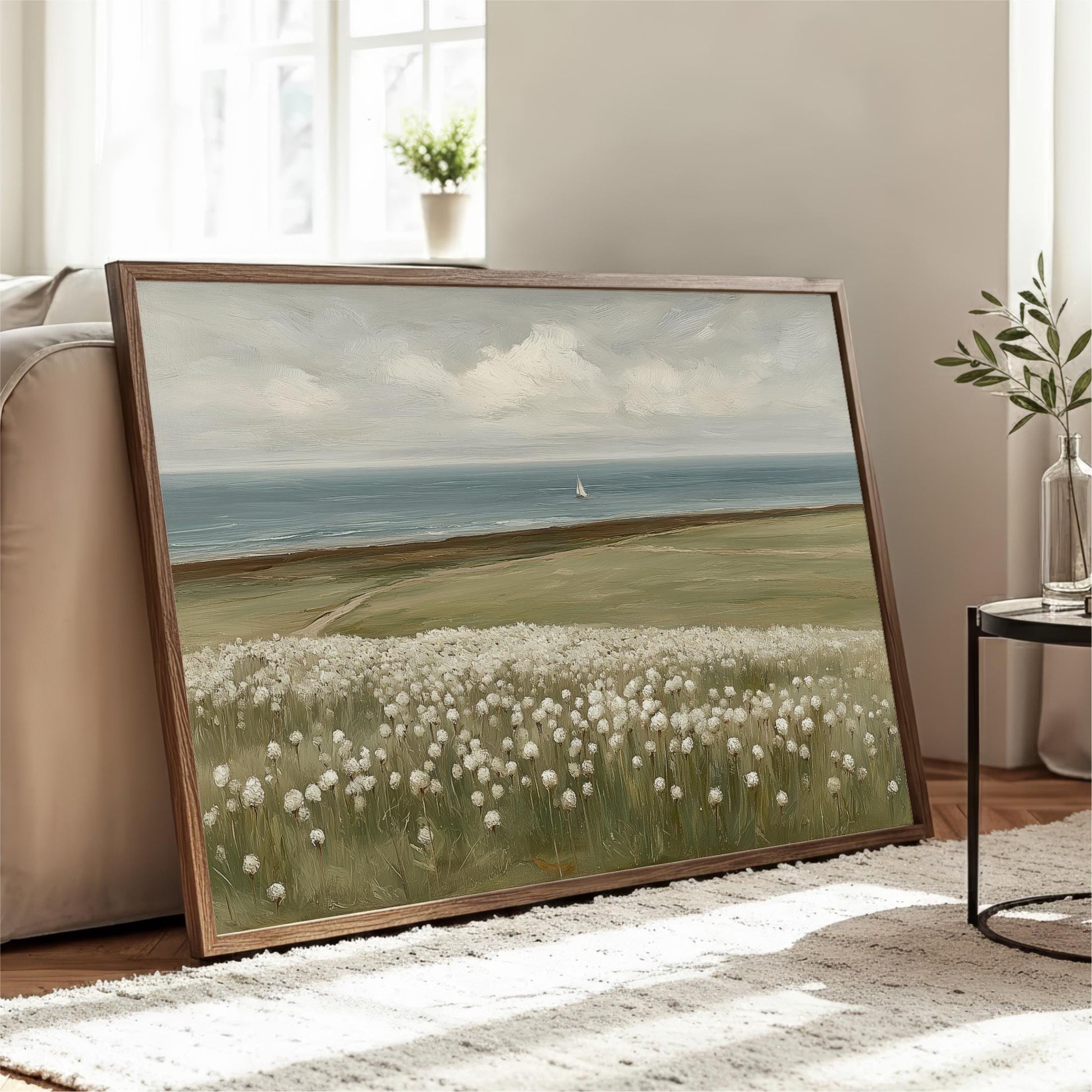 A large framed painting depicting a serene landscape with a field of white flowers, a sailboat on the water, and a cloudy sky.