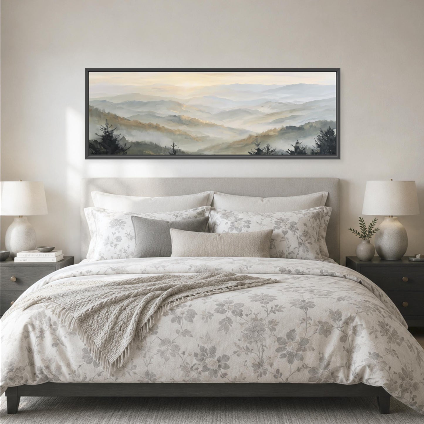 a large bed with a floral bedspread and pillows, flanked by two nightstands with lamps. Above the bed is a large framed landscape painting depicting a mountain range with a hazy, misty atmosphere.